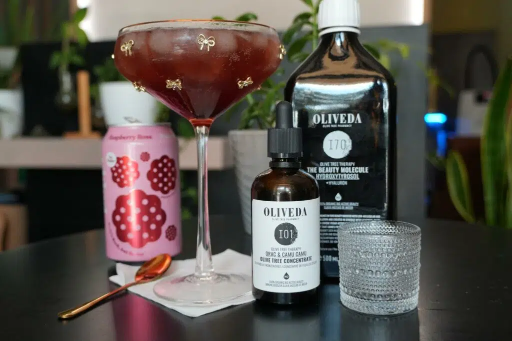 A stylish drink setup featuring Olive Rose beauty products and mixers on a black table.